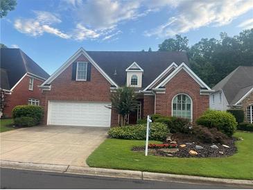 Charming brick home featuring an attached garage, manicured lawn, and mature landscaping at 3812 Mine Creek Ln, Marietta, GA 30062