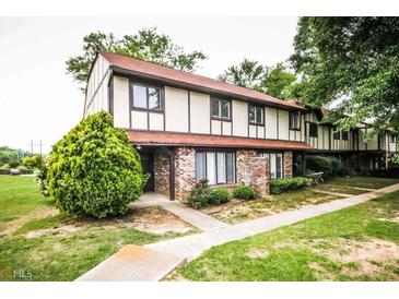 Two-story townhouse boasts brick accents, a red roof, and a well-maintained front yard with charming landscaping at 1200 Ashborough Se Ter # A, Marietta, GA 30067