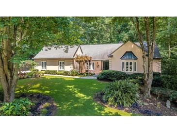 Charming one-story home boasting lush landscaping and mature trees, offering serene curb appeal at 1565 Kings Xing, Smoke Rise, GA 30087