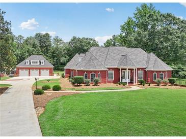 Beautiful brick home features a well-manicured lawn, lush landscaping, and a detached three-car garage at 2631 Young Rd, Stone Mountain, GA 30088