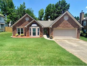 Charming one-story brick home featuring a manicured lawn, bay window, and attached two-car garage at 5022 Anclote Dr, Alpharetta, GA 30022