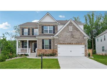 Beautiful two-story brick home with a well-manicured lawn, covered porch, and attached two-car garage at 5545 Adirondack Dr, Cumming, GA 30040