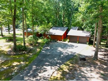 Unique exterior featuring two-car garage and a driveway, surrounded by mature trees and lush greenery at 686 Hillwood Ct, Dacula, GA 30019