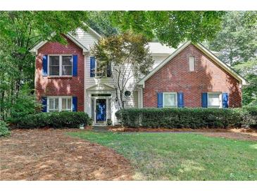 Charming two-story home featuring a brick facade, blue shutters, and a well-manicured front lawn at 6520 Fairfield Trce, Suwanee, GA 30024