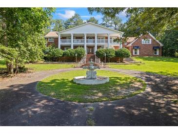 Stately two-story brick home with white columns and a circular driveway featuring a charming water fountain at 1961 Luke Edwards Rd, Dacula, GA 30019