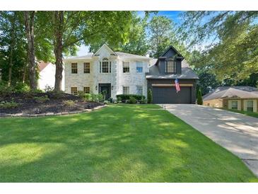 Charming white-brick home featuring a well-manicured lawn and a two-car garage with an American flag at 4385 Pinehollow Court Ct, Alpharetta, GA 30022