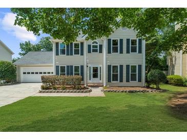 Charming two-story home with a well-maintained lawn, attached garage, and inviting front entrance at 1410 Kingfield Dr, Johns Creek, GA 30005