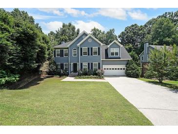 Charming two-story home featuring a well-manicured lawn, two-car garage and mature trees at 5176 Shotwell St, Woodstock, GA 30188