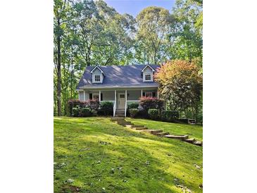 Charming cottage-style home featuring a lush, green lawn and mature trees for added privacy at 713 Trickum Valley Dr, Woodstock, GA 30188