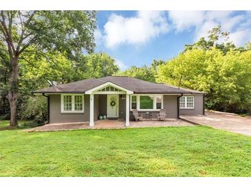 Charming single-story home with well-manicured lawn, mature trees and a cozy front porch with seating at 2123 Garden Cir, Decatur, GA 30032