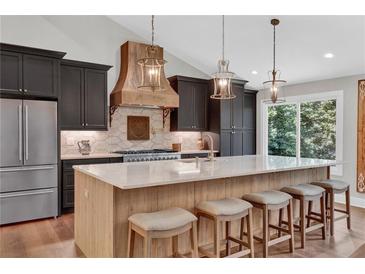 Stunning kitchen with a large island with seating, custom cabinetry, and pendant lighting at 230 Thistlewood Ln, Roswell, GA 30075
