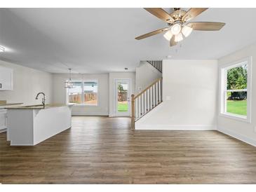 Bright, open-concept living room featuring hardwood floors, a ceiling fan, and a view to the backyard at 5350 Mercedes Dr, Cumming, GA 30041