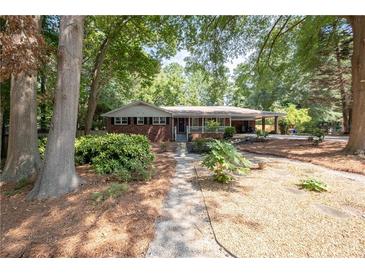 Charming single-story brick home with inviting front porch, lush landscaping, and a welcoming walkway at 4138 Hickory Dr, Powder Springs, GA 30127
