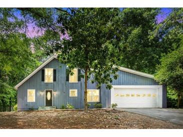 Charming blue home with attached garage and mature trees in the front yard at 3617 Lassiter Rd, Marietta, GA 30062