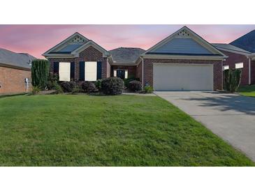 Charming brick home with a well-manicured lawn and two-car garage under a sky painted with hues of pink and orange at twilight at 1550 Rolling View Dr, Cumming, GA 30040
