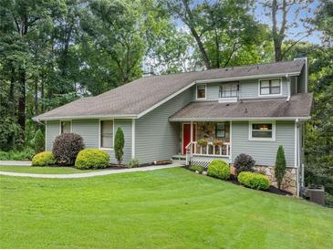 Charming two-story home featuring a manicured lawn, vibrant landscaping, and a welcoming red front door at 162 Nouveau Sw Ct, Lilburn, GA 30047