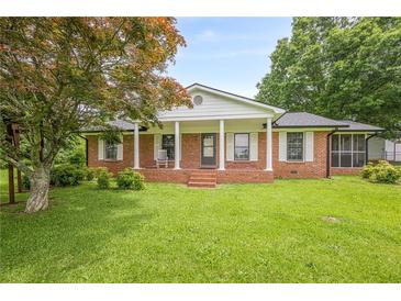 Charming brick home featuring a covered front porch and well-maintained lawn in a serene setting at 5709 Center Hill Church Rd, Loganville, GA 30052