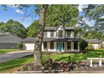 Charming two-story home with a well-maintained front yard, attached garage and a pop of color with an aqua-colored front door at 8649 Cedar Creek Rdg, Riverdale, GA 30274