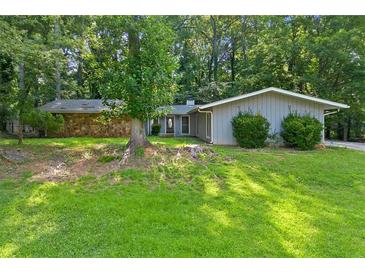 Charming ranch-style home with stone accent and mature trees, situated on a lush green lawn at 1328 Hidden Hills Pkwy, Stone Mountain, GA 30088