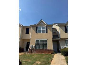 Charming townhome with tan facade, multiple windows, and a neatly maintained lawn at 2390 Coach Way, Jonesboro, GA 30236