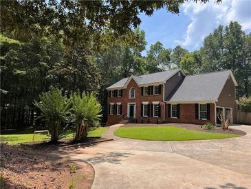 Beautiful brick home with a circular driveway and meticulously manicured lawn at 10560 Haynes Bridge Rd, Alpharetta, GA 30022