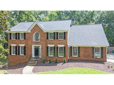 Charming brick home with black shutters, green landscaping, and a well-manicured lawn at 10560 Haynes Bridge Rd, Alpharetta, GA 30022