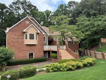 Charming brick home with bay window, manicured landscaping, and inviting staircase to a covered porch at 4027 Wood Acres Court Ct, Duluth, GA 30096