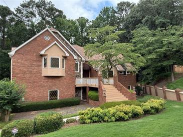 Charming brick home featuring mature landscaping, a cozy front porch, and a welcoming entrance with staircase at 4027 Wood Acres Ct, Duluth, GA 30096
