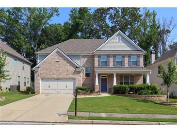 Charming two-story brick home featuring blue shutters, a landscaped yard, and a two-car garage at 1087 Halletts Peak Pl, Lawrenceville, GA 30044