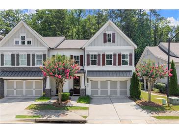 Charming townhome featuring gray siding, brick accents, a two-car garage, and a beautifully landscaped front yard at 109 Bellehaven Dr, Woodstock, GA 30188