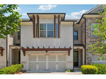 Charming townhome featuring a two-car garage, white brick facade, and manicured landscaping at 2058 Glenview Park Cir, Duluth, GA 30097