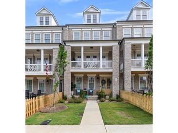 Charming townhouse featuring a brick facade, second-story balconies, manicured landscaping, and inviting entryways at 579 Brashy St, Woodstock, GA 30188
