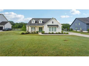 Charming modern farmhouse featuring a well-manicured lawn, black roof and a pair of rocking chairs at 4720 Down Setting Rd, Cumming, GA 30028