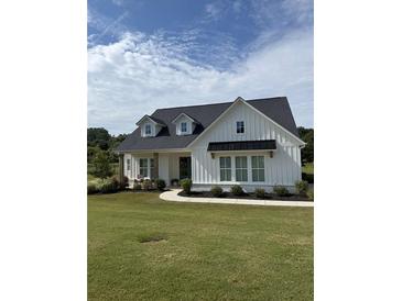 Charming white farmhouse with black roof, complemented by a well-manicured lawn and a walkway to the inviting front porch at 4720 Down Setting Rd, Cumming, GA 30028