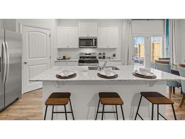Bright kitchen boasts white cabinets, stainless steel appliances, and a large island with seating at 4944 Jatoba Rd, Acworth, GA 30101