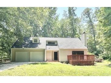 Charming home featuring an attached garage and a wooden porch, surrounded by lush greenery at 5968 Hilltop Dr, Douglasville, GA 30135