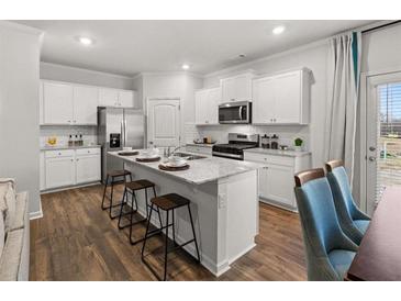 A bright kitchen with an island, granite countertops, stainless steel appliances, and hardwood floors at 4948 Jatoba Rd, Acworth, GA 30101