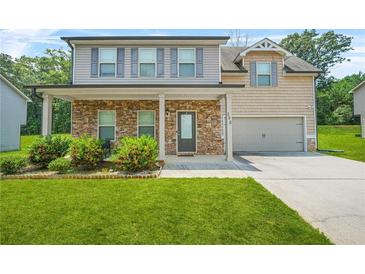 Charming two-story home with stone accents, covered porch, lush lawn and mature landscaping at 588 Joneus Dr, Mcdonough, GA 30252