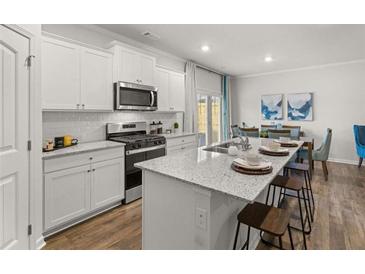 Modern kitchen featuring white cabinetry, stainless steel appliances, and a granite island with seating at 4958 Jatoba Rd, Acworth, GA 30101