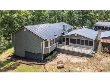 A rear exterior view shows a metal roof, enclosed porch, open deck and wooded lot at 261 Clayton Trl, Canton, GA 30114