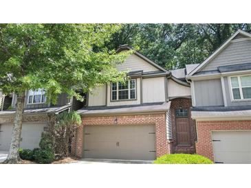 Charming townhouse featuring a two-car garage, brick accents, and mature trees at 109 Creighton Ln, Marietta, GA 30008