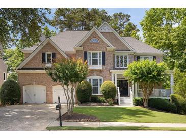 Charming two-story brick home with a well-manicured lawn, mature trees, and a two-car garage at 2030 Darien Park Dr, Roswell, GA 30076