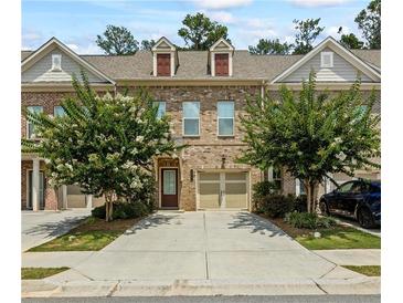 Inviting brick townhome with a two-car garage and well-manicured landscaping at 261 Mahone Dr, Lilburn, GA 30047