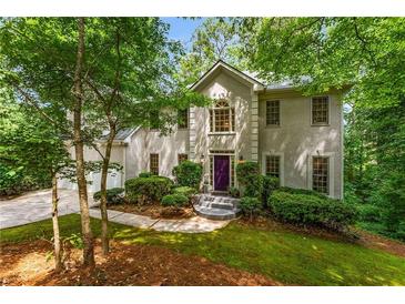 Charming home featuring a stucco exterior, lush landscaping, and a welcoming purple front door at 1950 Wenlok Ne Trl, Marietta, GA 30066