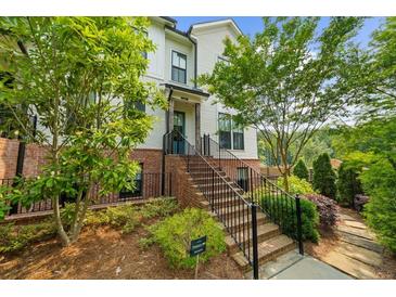 Charming two-story townhouse with brick accents, lush landscaping, and inviting stairway to the front door at 219 Phillips Ln, Alpharetta, GA 30009