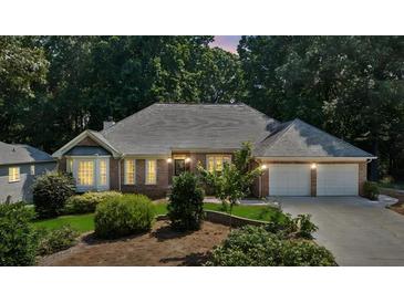 Charming brick home with a well-manicured lawn and a two-car garage nestled amongst mature trees at 5195 Overbend Trl, Suwanee, GA 30024