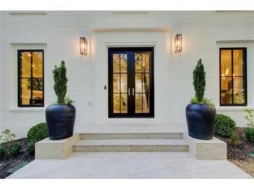Elegant front entrance with black double doors, modern lighting, and potted greenery on a white brick facade at 6090 River Chase Cir, Atlanta, GA 30328