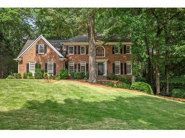 Stately brick home boasts lush lawn, mature trees, classic black shutters and well-maintained landscaping at 4971 Fairhaven Ne Way, Roswell, GA 30075