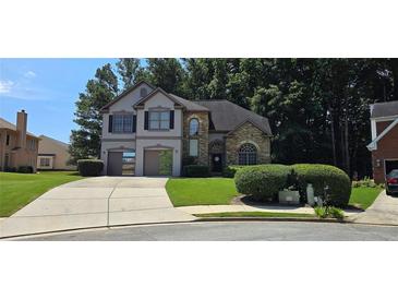 Two story home with a brick and stucco front, green lawn, and two car garage at 3310 Mcclure Woods Ct, Duluth, GA 30096
