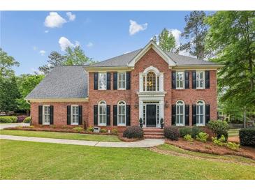 Beautiful two story brick home with a landscaped yard, black shutters and trimmed bushes in front at 730 Mount Oglethorpe Trl, Alpharetta, GA 30022